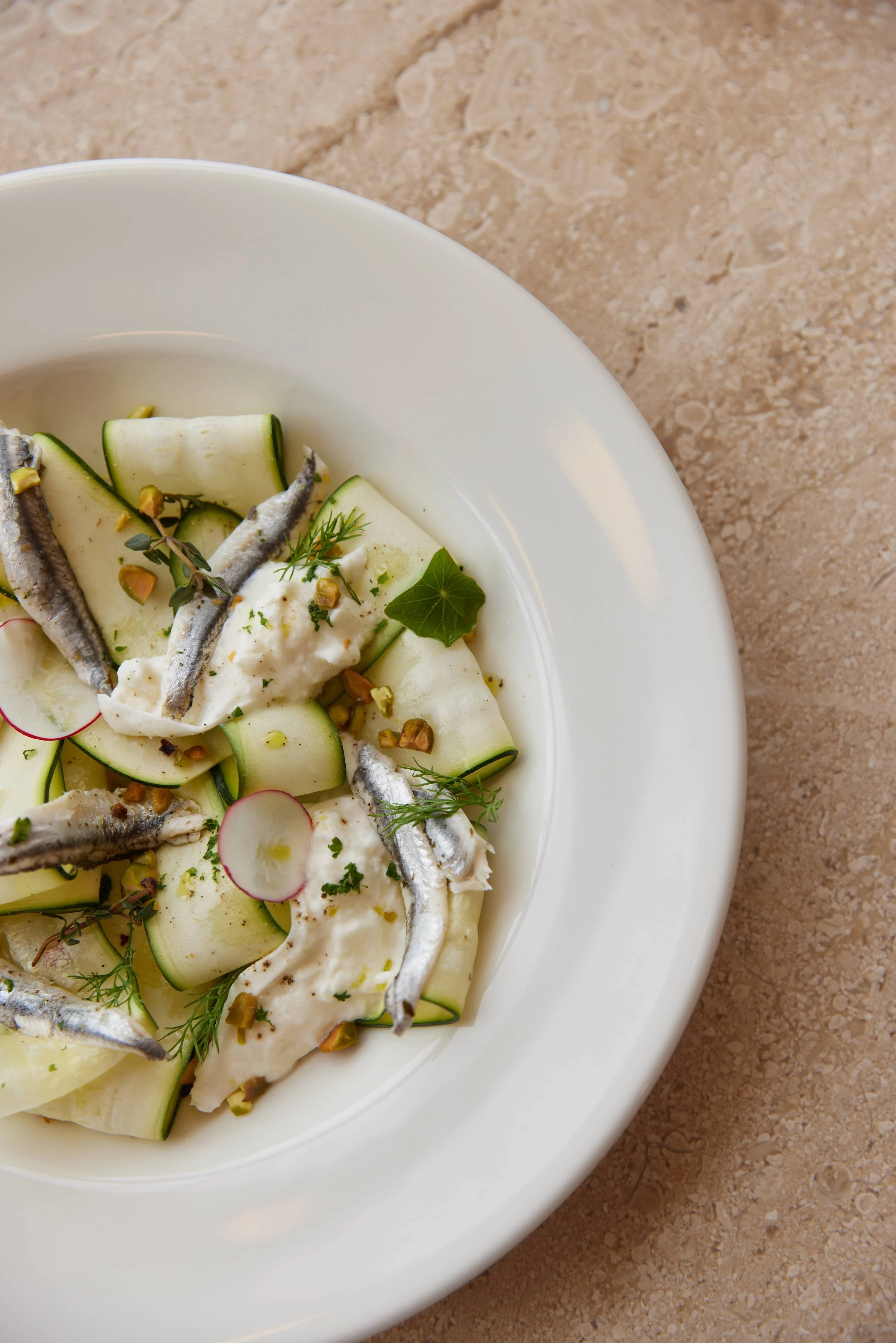 【早午餐推薦】「白鯷魚櫛瓜布拉塔起司」使用醃漬白鯷魚配上薄片櫛瓜，並佐上布拉塔起司及開心果，口味相當清爽。© Acme Tuya Tuya